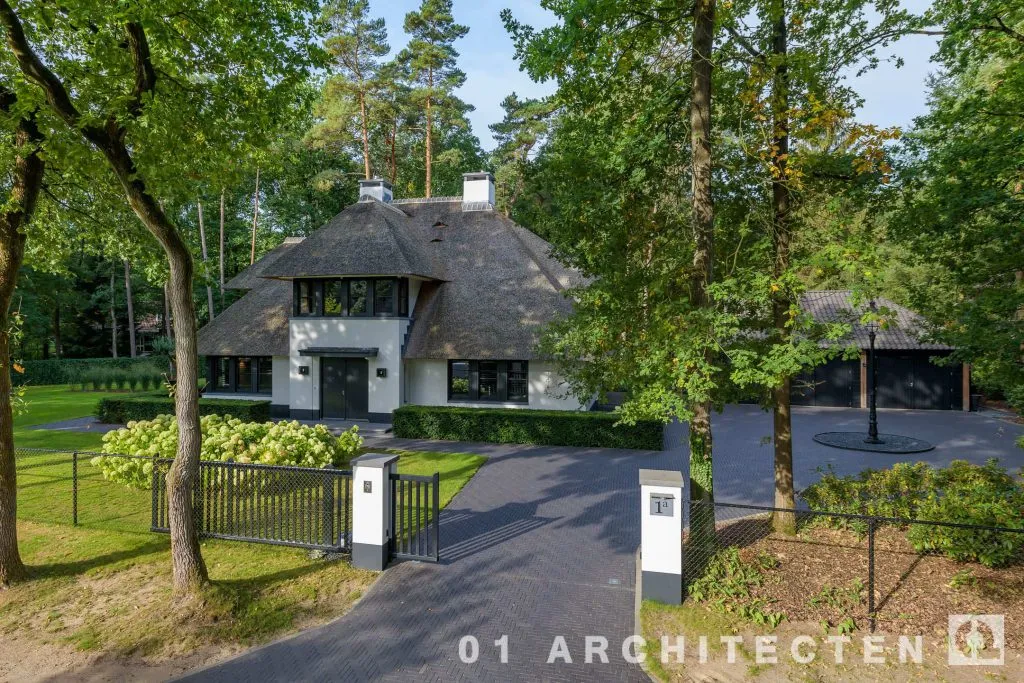 Rietgedekte villa met witte gevels in bosrijke omgeving
