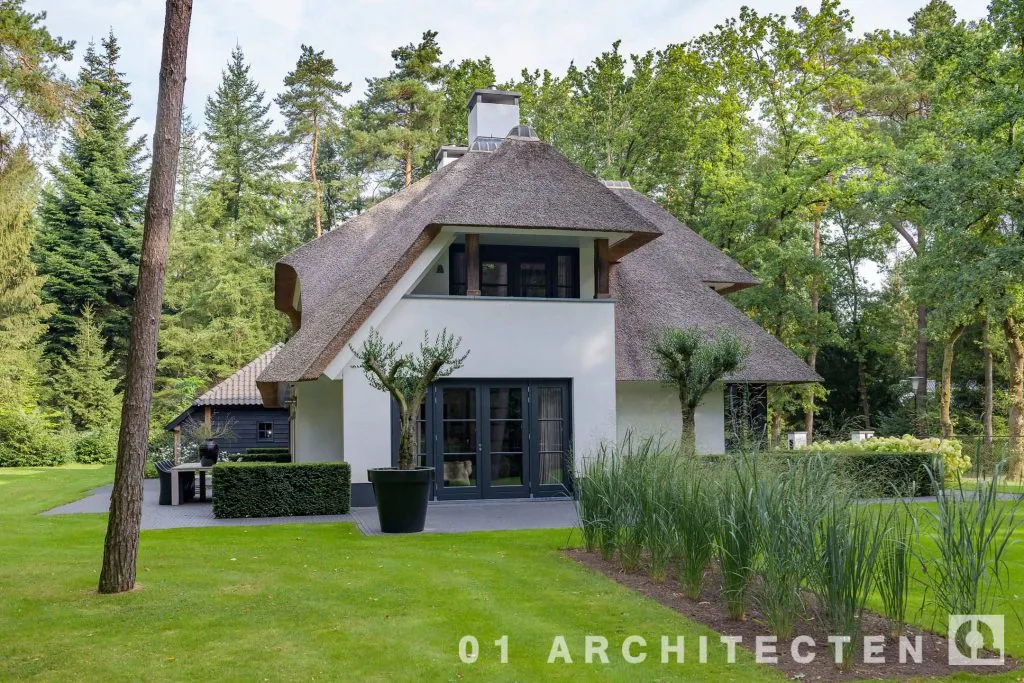 Gevel van de rietgedekte villa in Ugchelen met terugliggend balkon en grote rieten dakvlakken